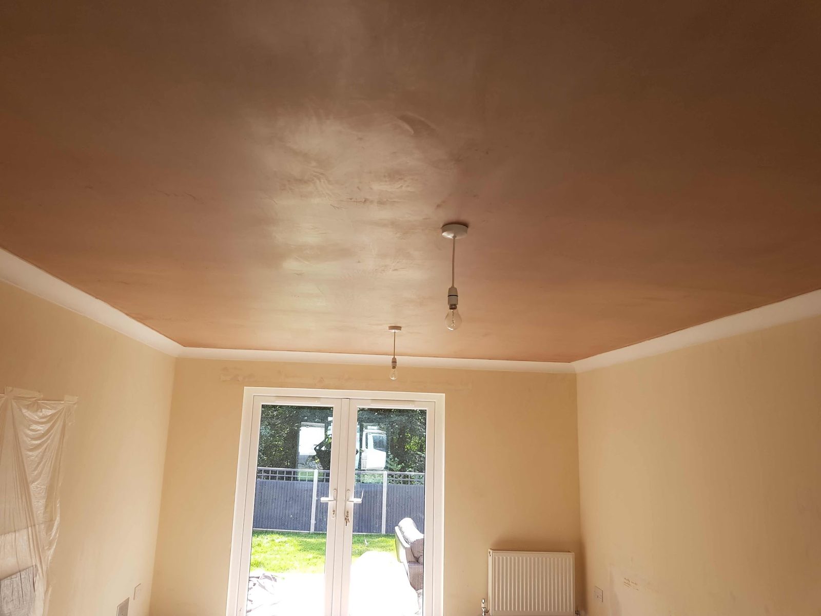 Room with a freshly skimmed ceiling and walls, French doors open to the garden