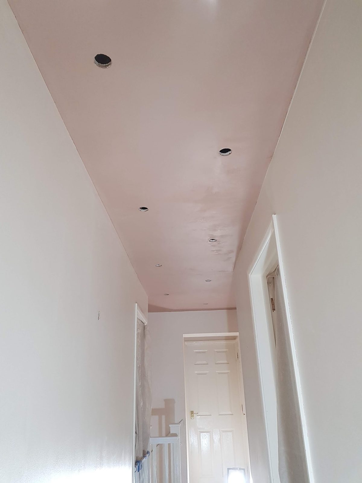 Landing ceiling freshly skimmed with holes cut for downlights