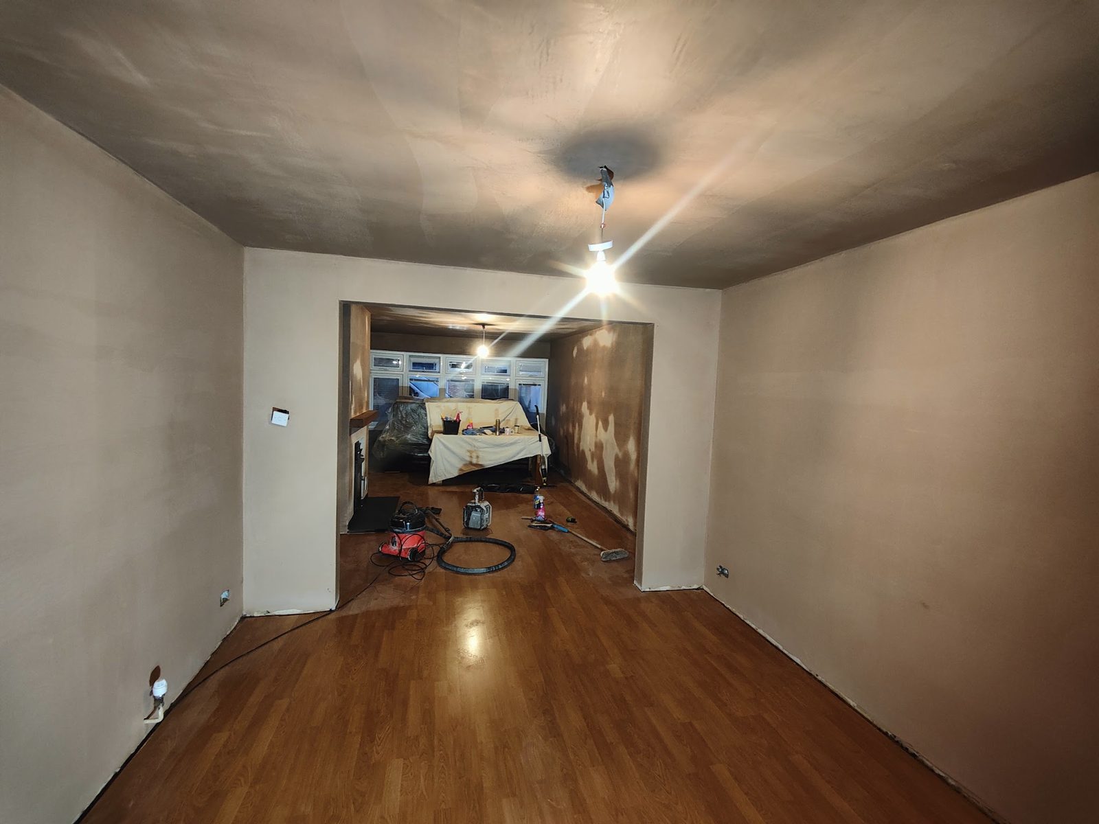 Through room with fresh plaster on walls and ceiling and a wooden floor