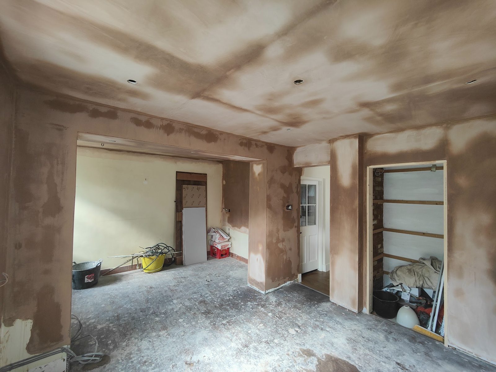 Stripped-out room with newly plastered walls around a wide opening