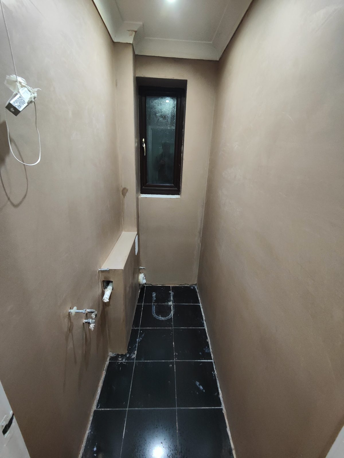 The same cloakroom with smooth finished plaster and a black tiled floor