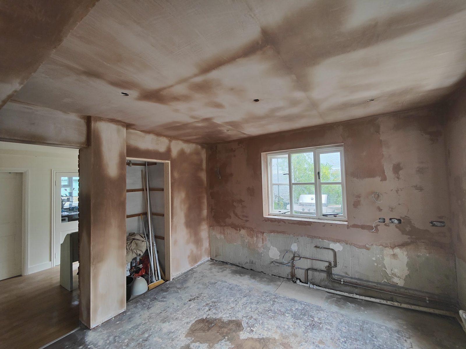 Room with fresh plaster around a wide opening, floor still bare