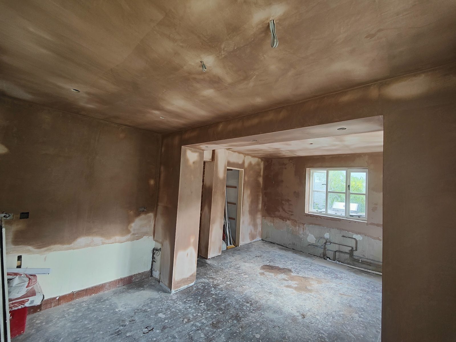 Freshly plastered room with a window, drying patches on the walls