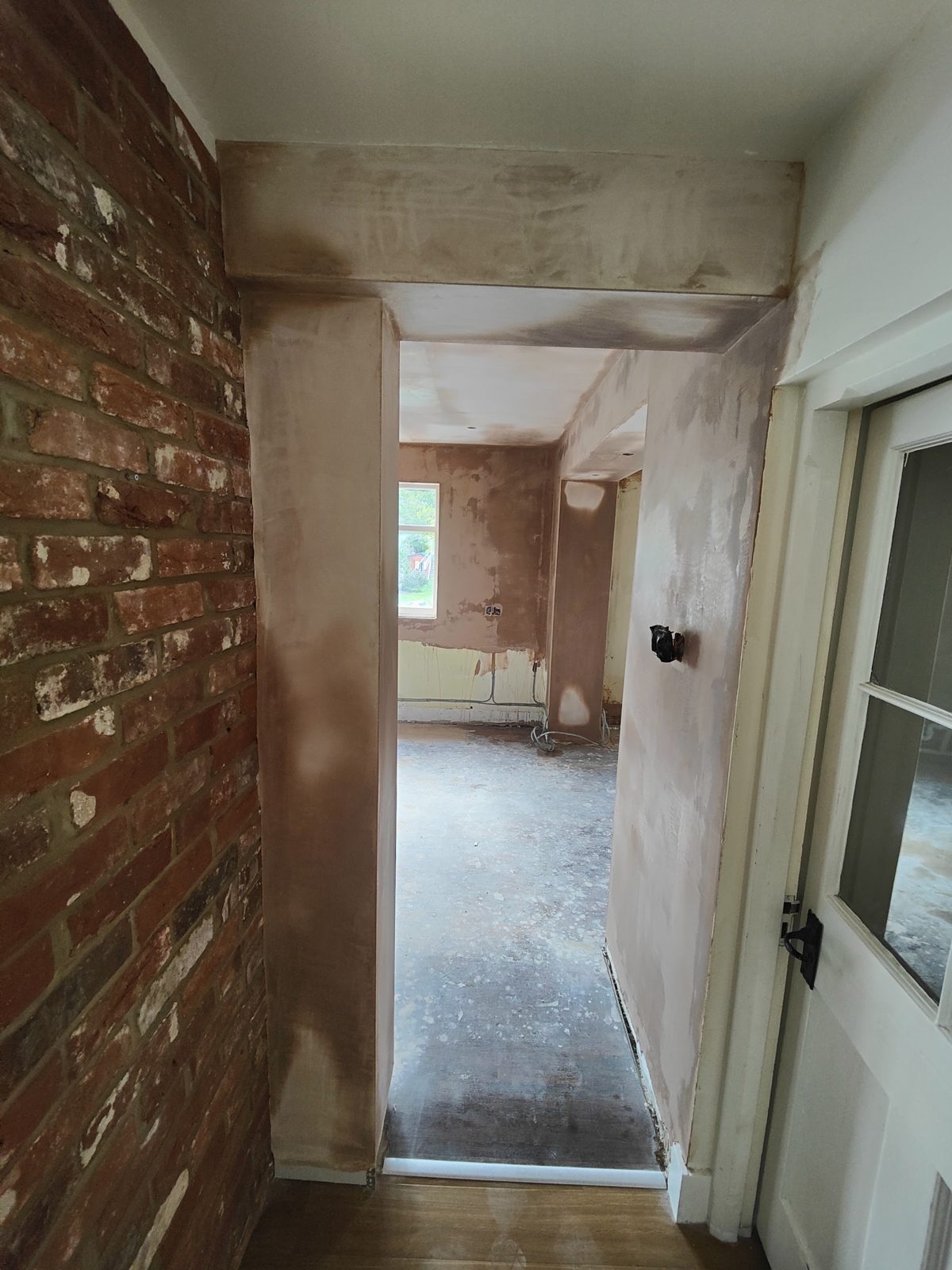 Hallway with fresh plaster beside an exposed brick wall