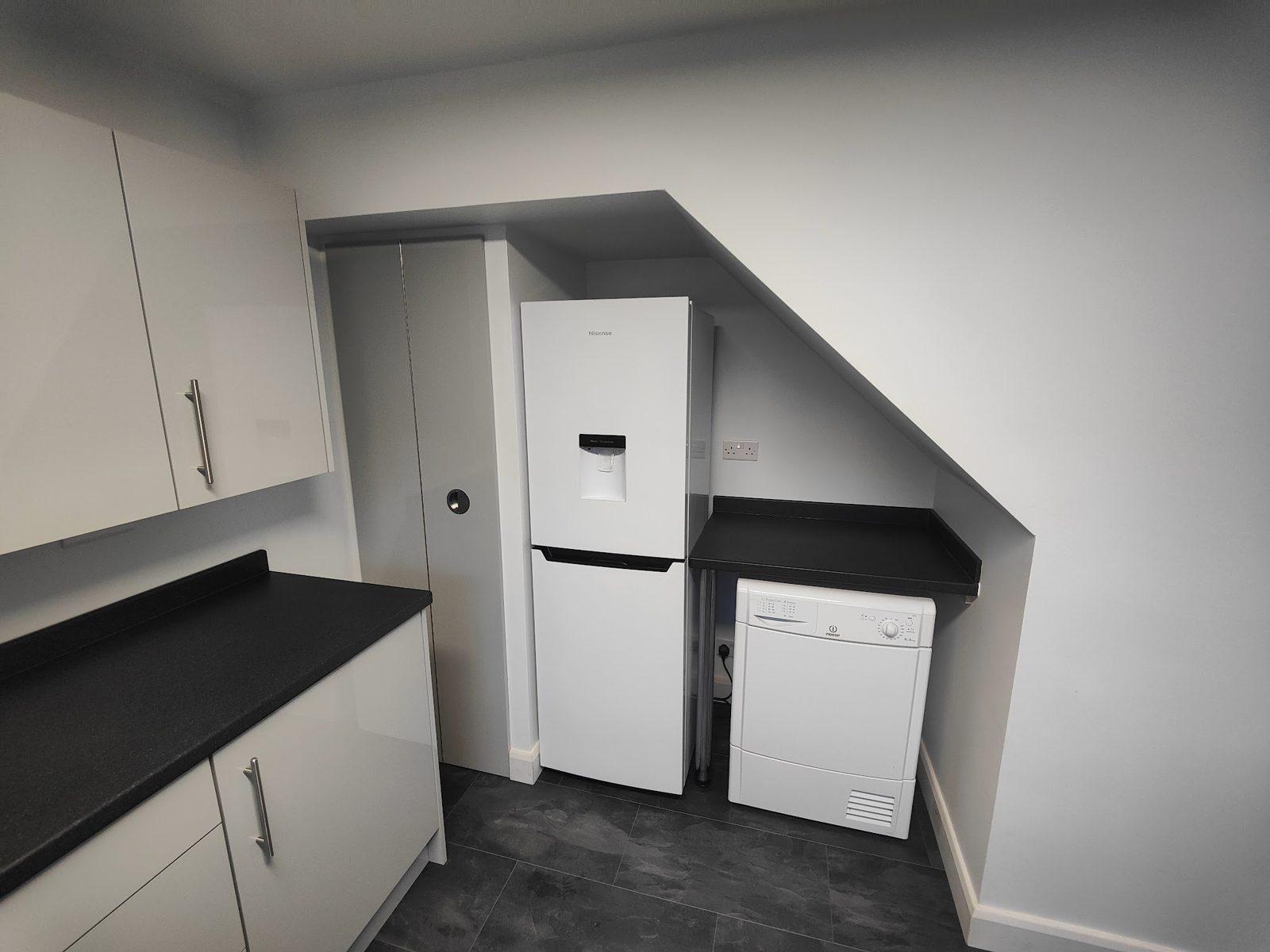 White kitchen with a fridge set into the alcove under the stairs