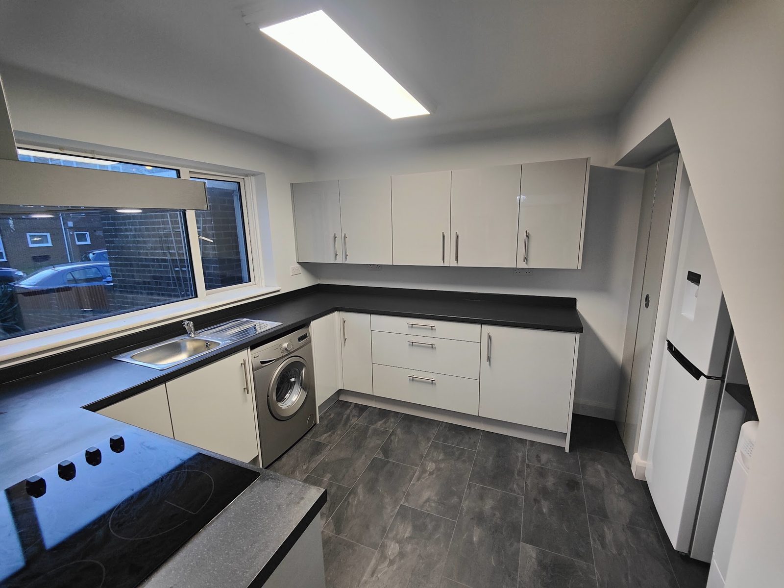 White kitchen with black worktops and fresh white walls