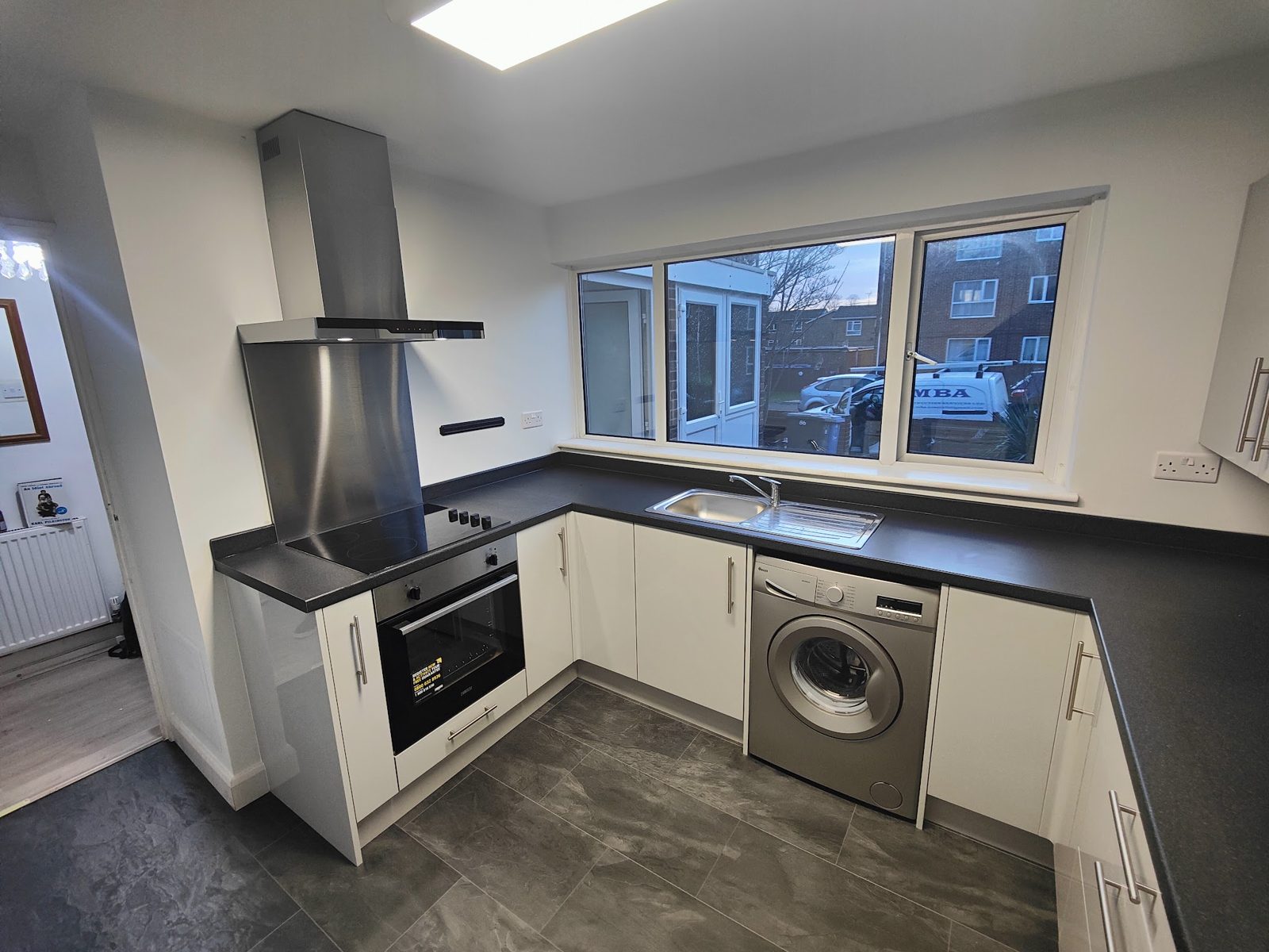 White kitchen with a chimney hood under the window